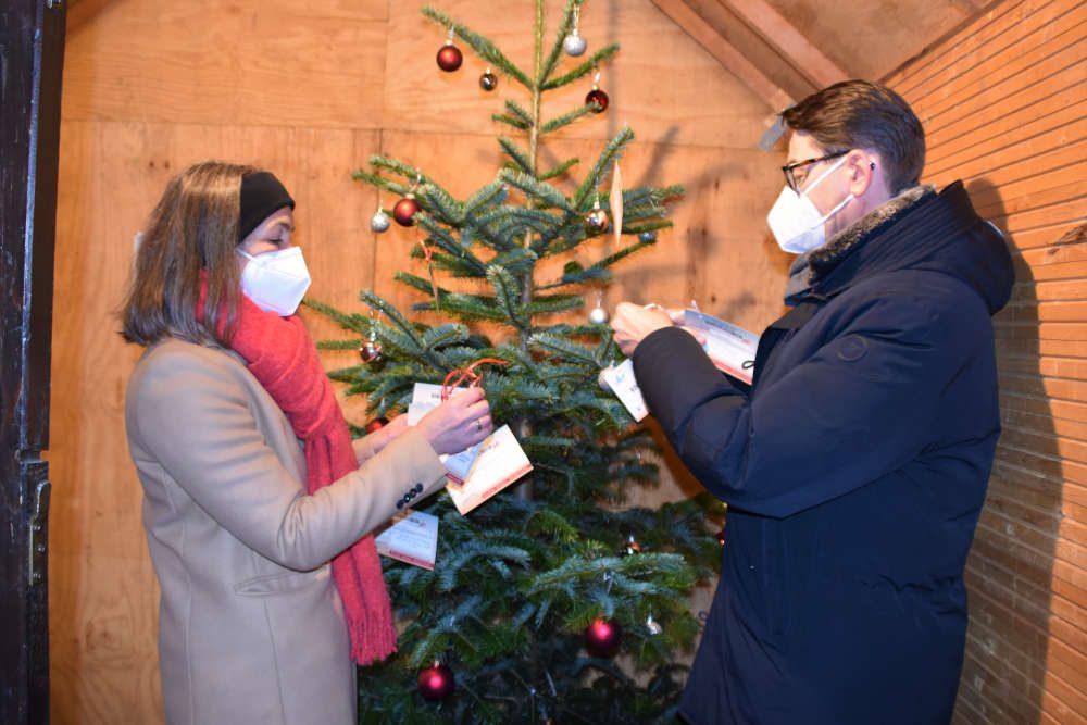Susanne Burgdörfer vom Haus der Familie und OB Thomas Hirsch hängen die Karten mit den Wünschen an den Kinderwunschbaum. (Quelle: Stadt Landau)